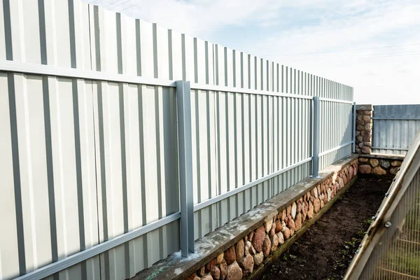 Installation of gray fence from metal profile.