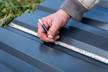 Bir işçi çimen arka planında metal bir levhayı işaretler..