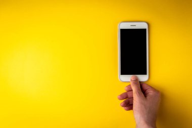 Sarı arka planda elleri olan cep telefonu..