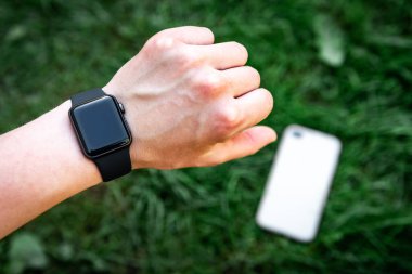Çimen arka planında akıllı saat ve cep telefonu.