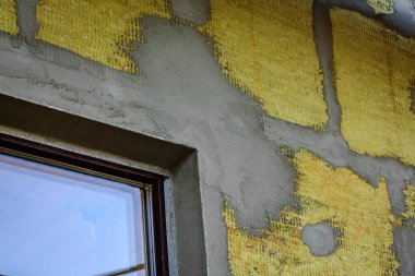 Mineral yünündeki fiberglasları güçlendirmek için yalıtımlı duvara yapıştırıcı katmanı sürüyorum..