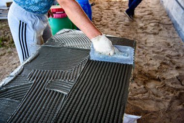 Ev yalıtımı için mineral yününe yapıştırıcı süren malalı işçi eli. Ev ısıtma enerjisinden tasarruf etmek için fiberglas levhalar.