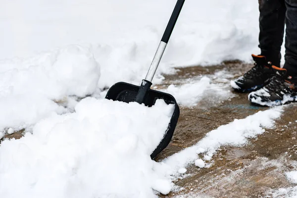Woman cleaning snow from sidewalk and using snow shovel.