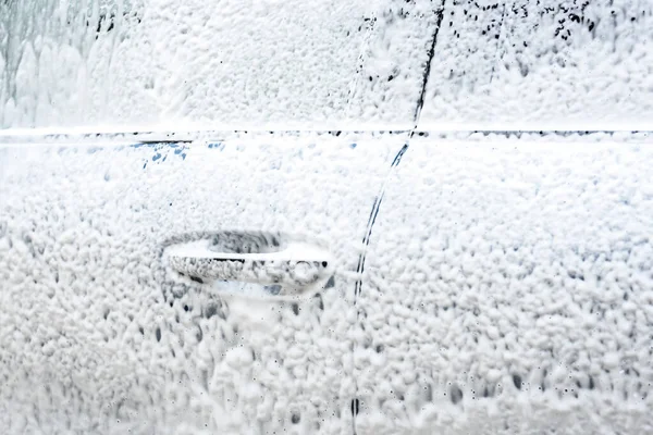 High pressure automobile cleaning with foam in car wash.