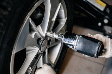 Garajda pnömatik ingiliz anahtarıyla lastik ya da tekerlek değiştirme yapan adam. Araba tekerleği değiştiriliyor..