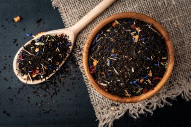 Siyah arkaplanda ahşap kasede kırmızı çay ve elma..