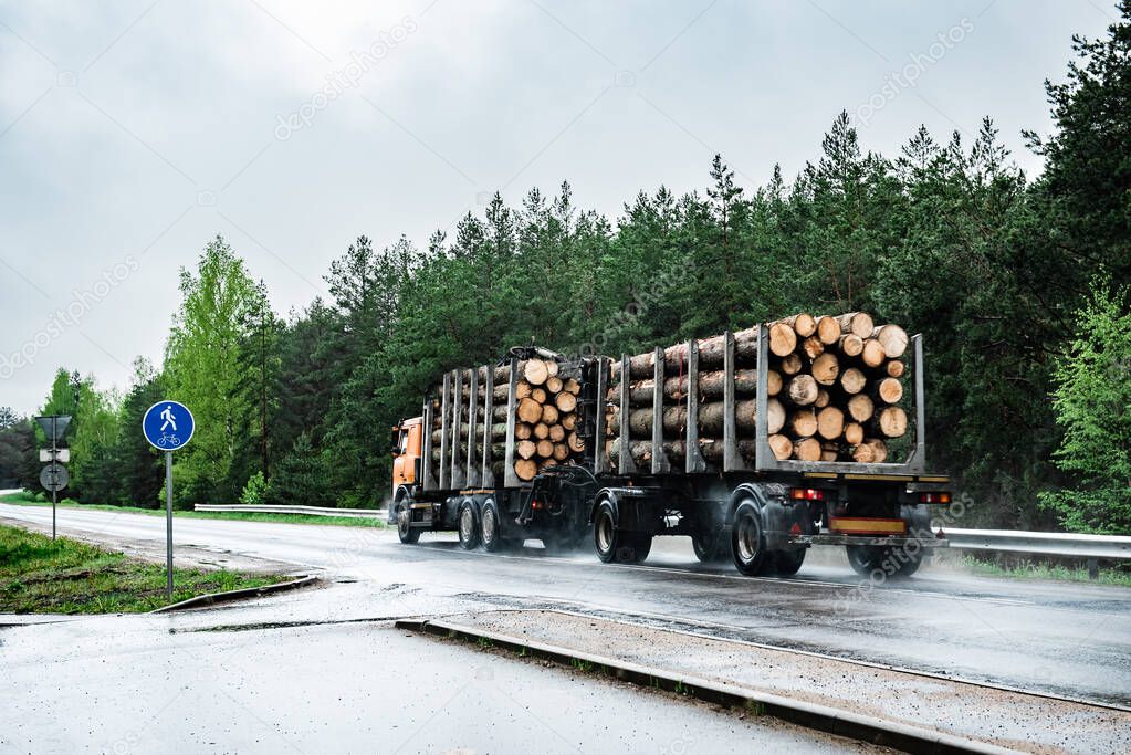Logging truck on road on rainy day.