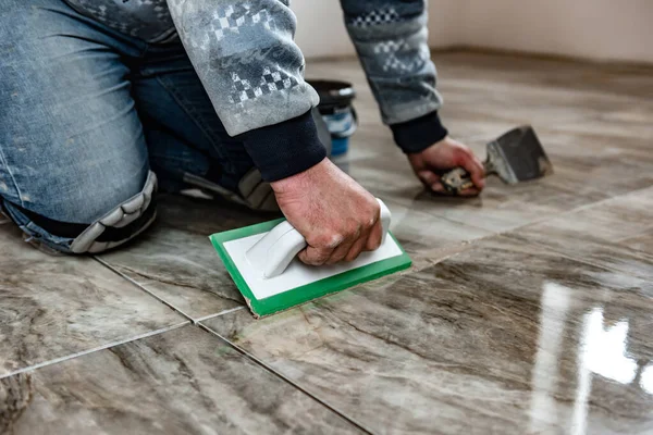 Grouting ceramic tiles. Tilers filling the space between tiles using a rubber trowel.