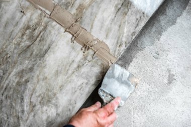 Döşemeye fayanslarla kaplı bej bir harç sürüyorum..