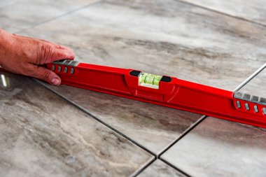 Worker checks the level of the tile floor.