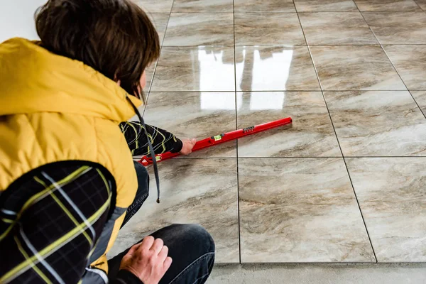 Worker checks the level of the tile floor.