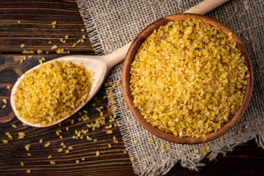 Koyu ahşap arka planda ahşap kasede bulgur..