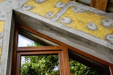 Mineral yünündeki fiberglasları güçlendirmek için yalıtımlı duvara yapıştırıcı katmanı sürüyorum..