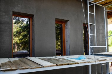 Applying fresh construction glue layer on insulated wall for covering fiberglass reinforcing mesh on mineral wool.