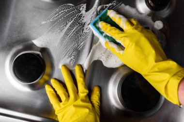 Sarı lastik eldivenlerle mutfak ocağını temizleyin..