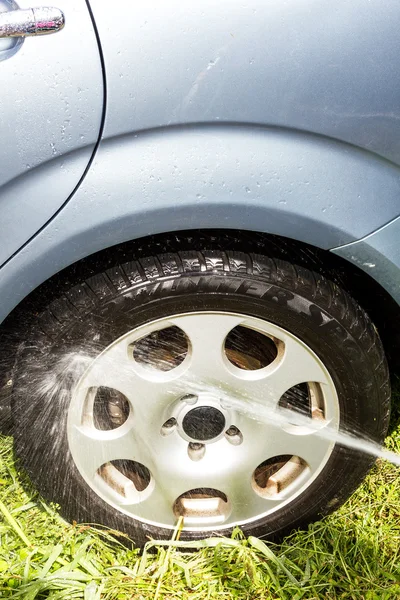 Шланг розбризкує воду на автомобільній шині — стокове фото