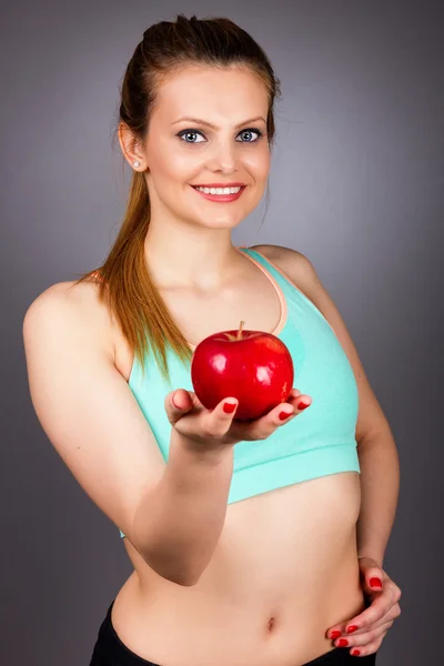 Retrato de cerca de una hermosa joven que muestra una manzana roja — Foto de Stock