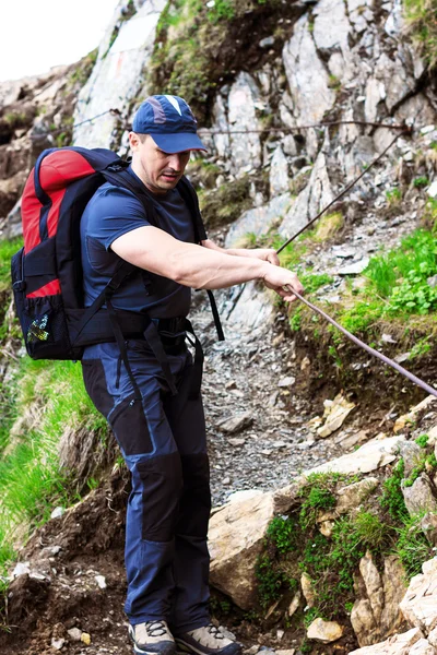 若い男吊りケーブルと険しい山岳道でハイキング — ストック写真