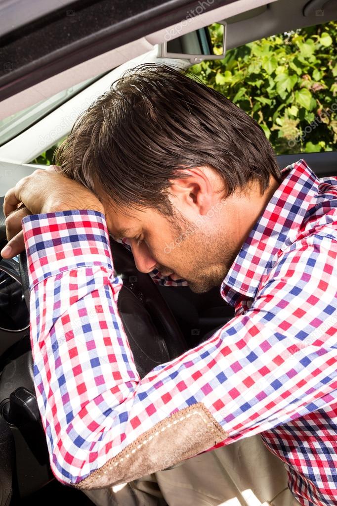 Exhausted driver resting on steering wheel 