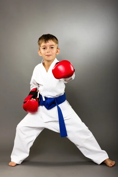 Niño pequeño con guantes rojos entrenamiento karate — Foto de Stock