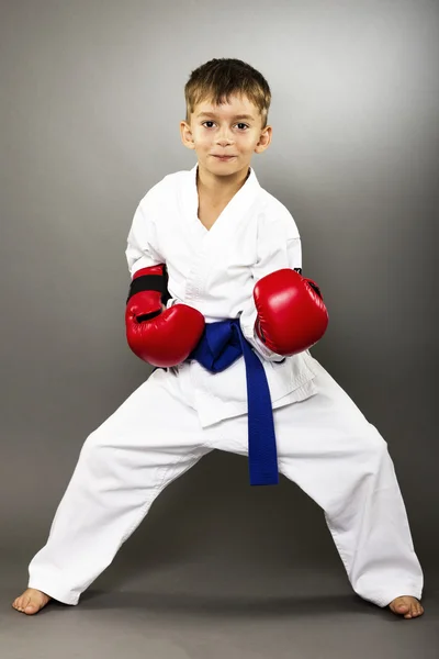 Niño pequeño con guantes rojos entrenamiento karate — Foto de Stock