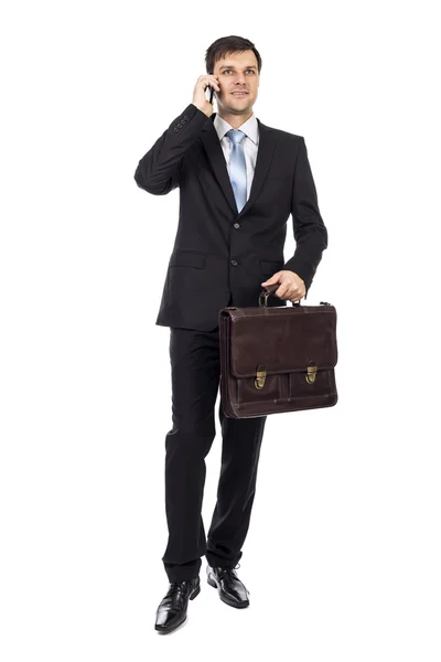 Handsome young business man holding a suitcase and talking on ph — Stock Photo, Image