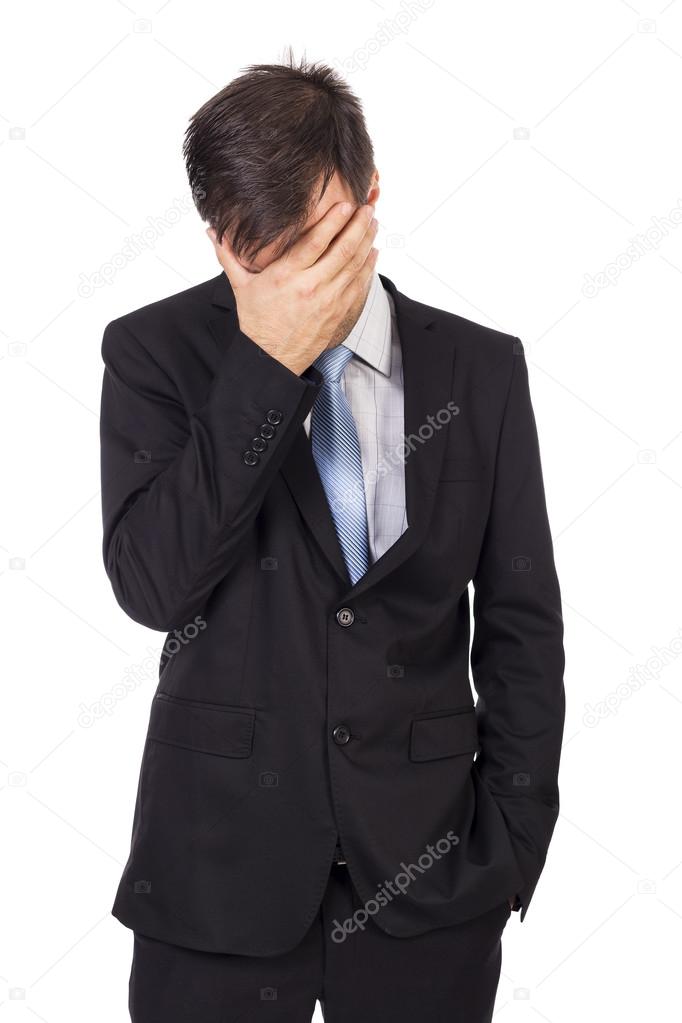 Portrait of exhausted young businessman covering his face with h