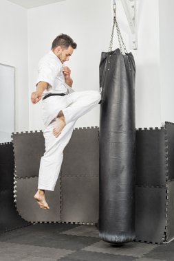 Athletic black belt karate giving a forceful knee kick during a clipart