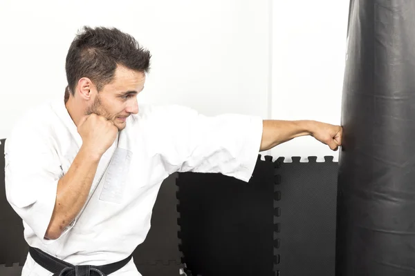 Ung man i kimono kasta slag på en tung slagsäck — Stockfoto