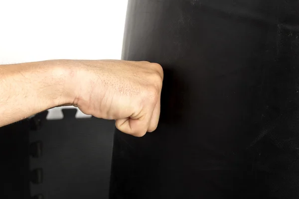 Junger Mann schlägt mit der Faust auf einen schweren Sack — Stockfoto