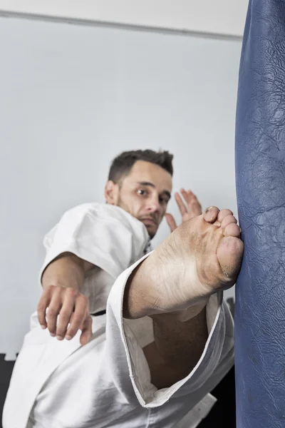 Atletismo negro cinturón de karate dando una patada fuerte pie a un boxi — Foto de Stock