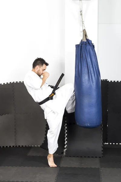 Atletische zwarte gordel karate geven een krachtige knie-kick tijdens een — Stockfoto