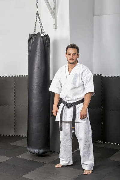 Sportovní černý pásek karate stojící vedle boxu ba Stock Obrázky