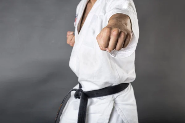 Junger Mann im weißen Kimono und schwarzem Gürtel trainiert Kampfkunst Stockfoto