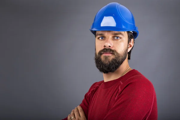 Joven trabajador de la construcción confiado con el hardhat y los brazos cruzados —  Fotos de Stock