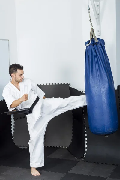 Luchador de karate atlético dando una patada fuerte en el pie a una pesada b — Foto de Stock