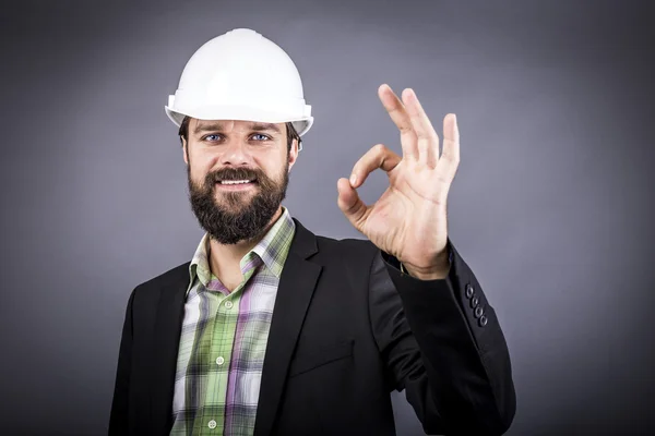 Glad ung ingenjör med vita hardhat visar ok tecken — Stockfoto