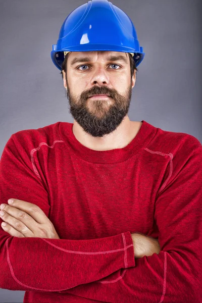 Joven trabajador confiado con el hardhat y los brazos cruzados — Foto de Stock