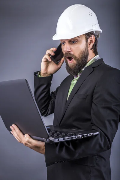 Portrait of a surprised engineer holding his laptop and having a — Stock Photo, Image