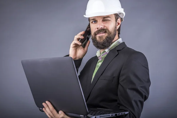 Succesvolle ingenieur praten over de telefoon en het bedrijf van zijn laptop — Stockfoto