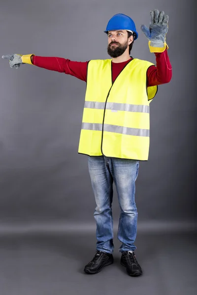 Junger Bauarbeiter mit harter Lenkung des Verkehrs Stockbild