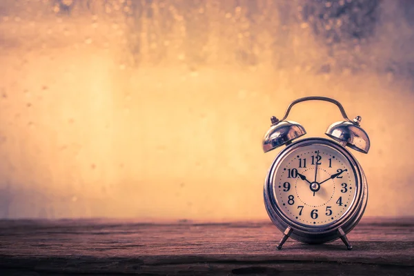 Despertador retro en la mesa frente a la lluvia —  Fotos de Stock