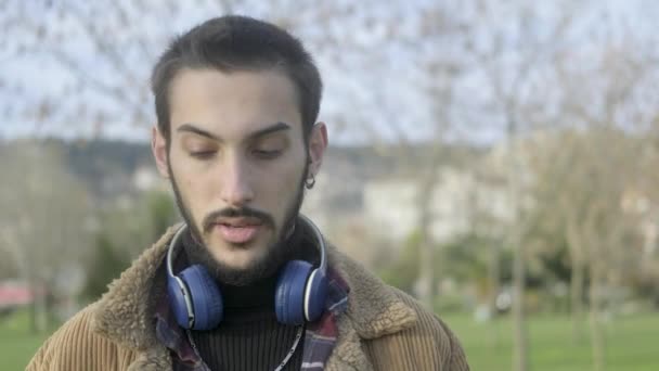 Молодий чоловік носить навушники на вусі — стокове відео