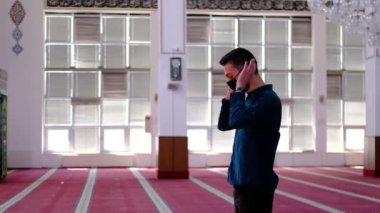 Maskeli camide ibadet eden adam.