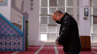 Yaşlı adam maskeli camiye dua ediyor.