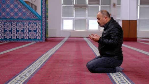 Stařec zvedá ruce a modlí se z mešity — Stock video