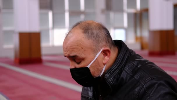 Starý muž v masce zvedá ruce a modlí se z mešity — Stock video