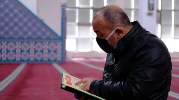 Starší muž v masce četl mešitu Koránu — Stock video