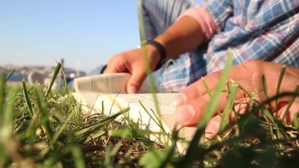 Junger Mann liest Buch im Park — Stockvideo