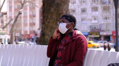 Siyah genç adam maskeli telefonu.